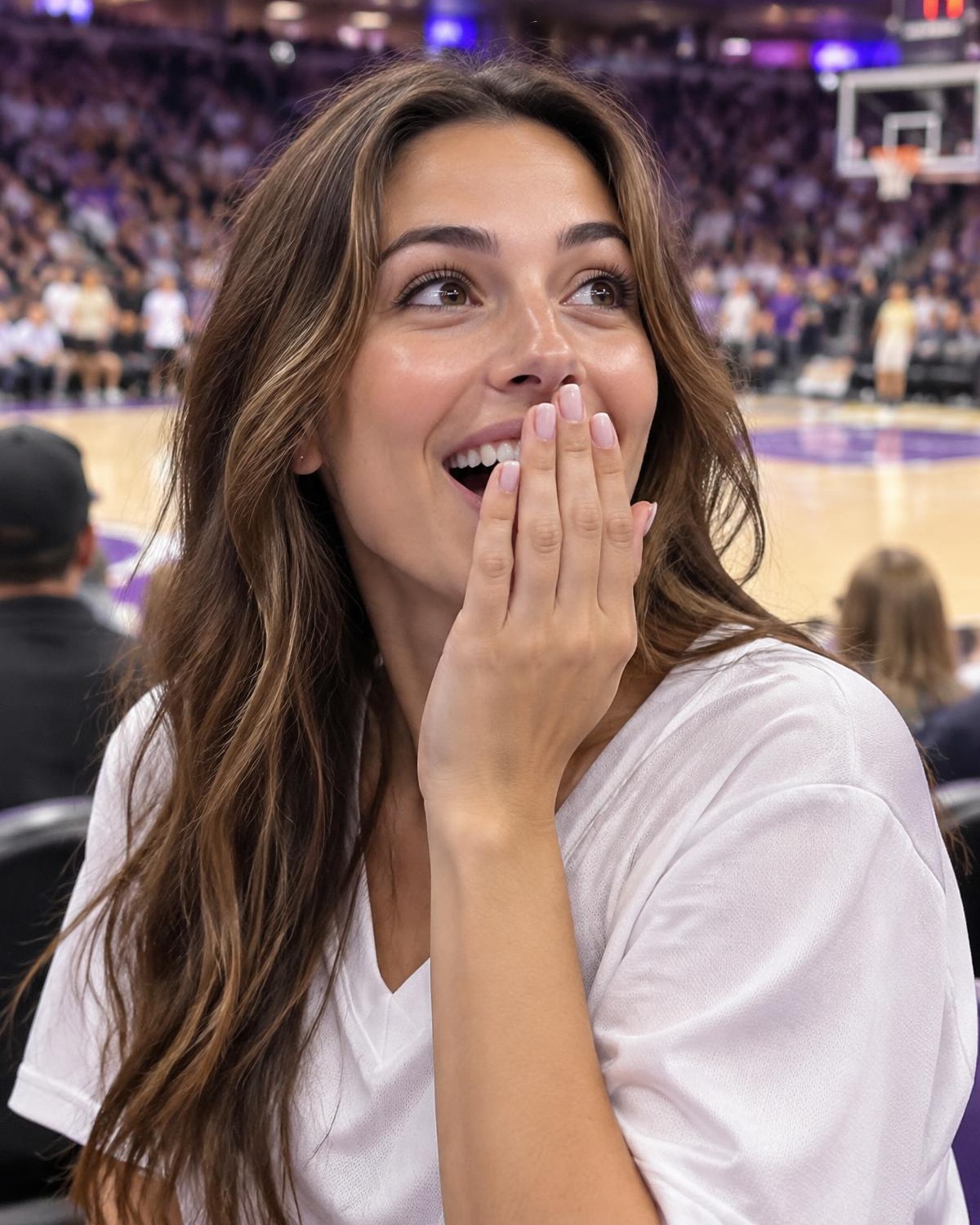 A fan covers her mouth in surprise at her courtside seat.